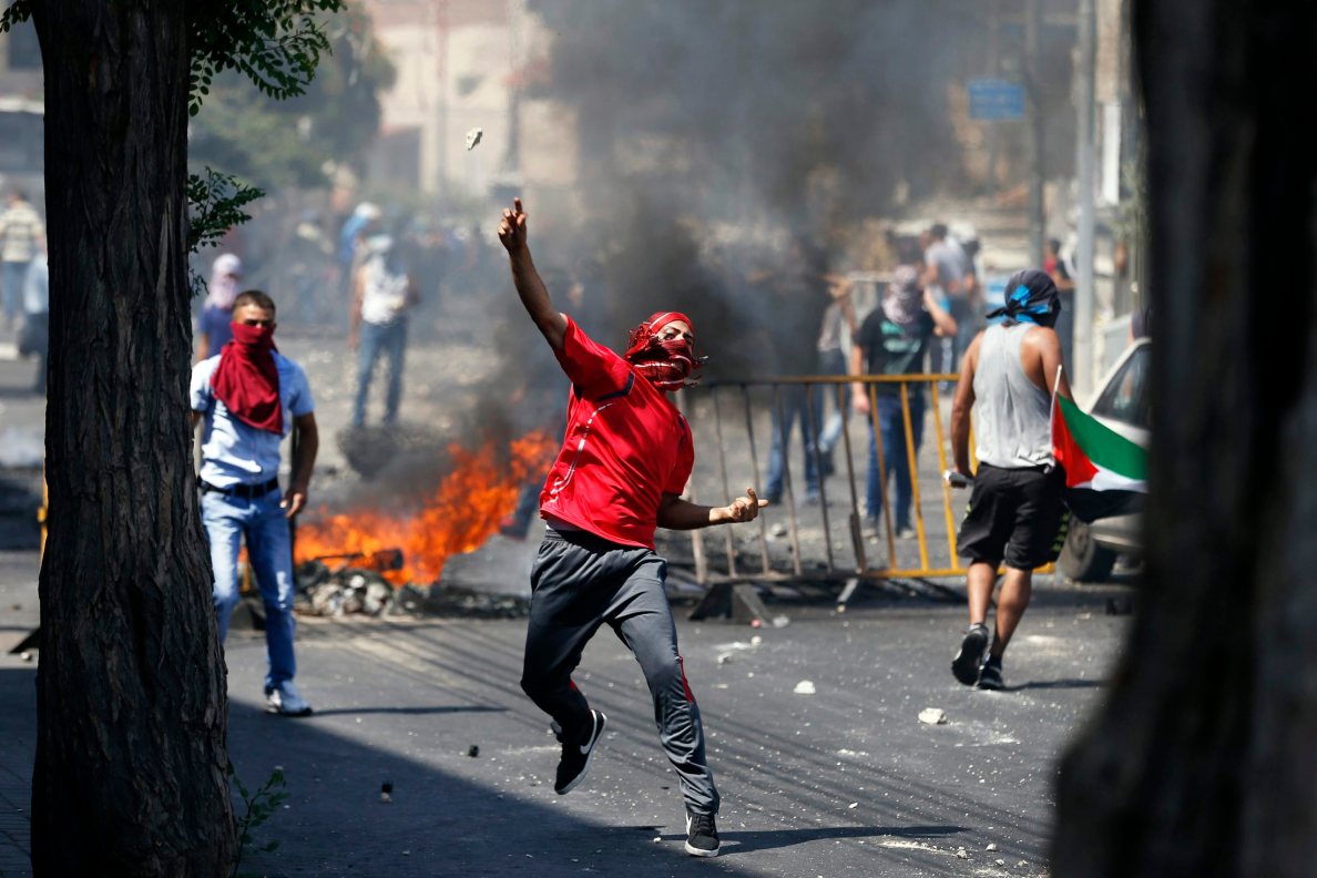 Palestinian throws a stone during clashes with Israeli police after prayers on the first Friday of Ramadan in East Jerusalem